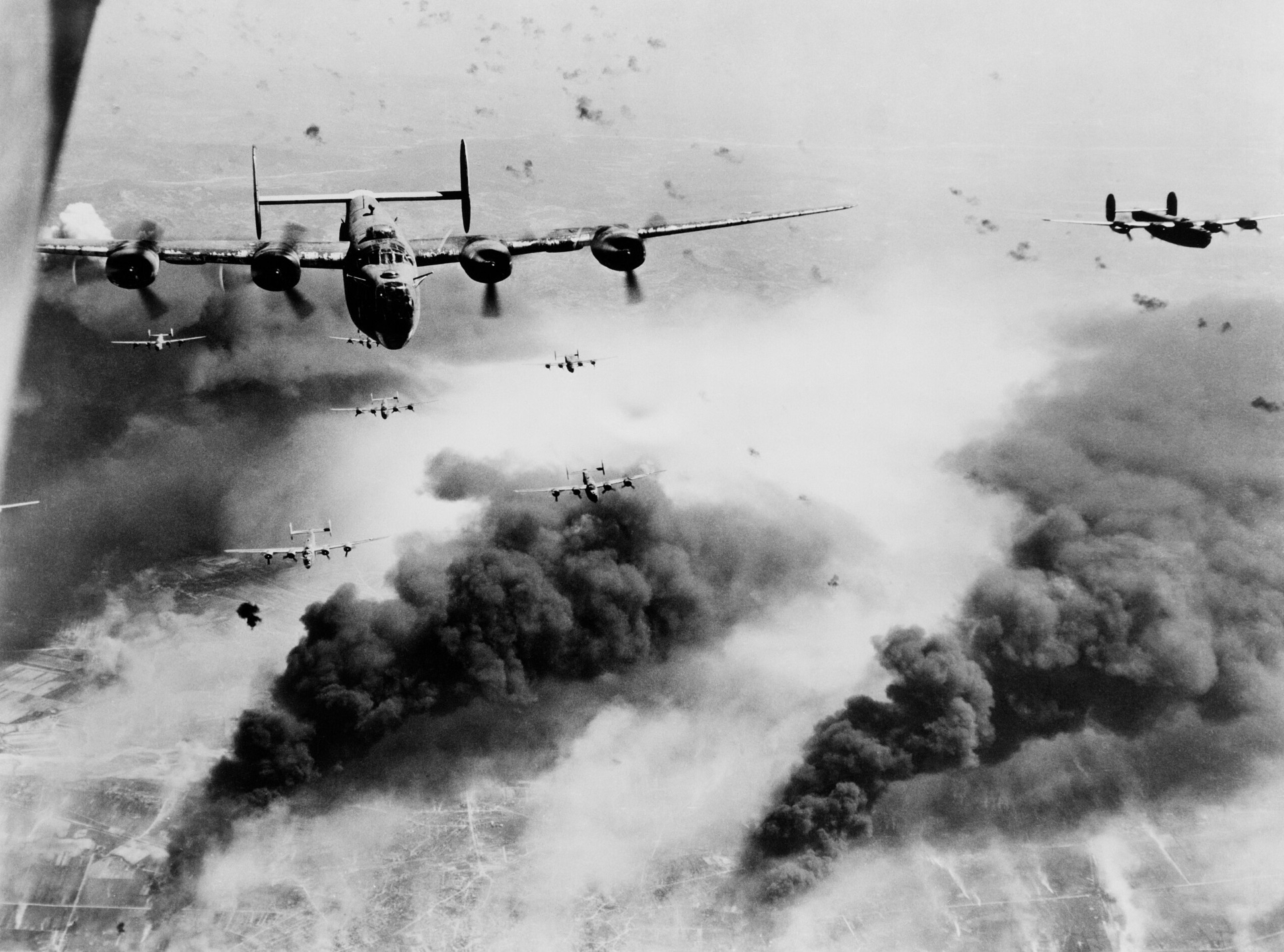15th Air Force B-24s flying through flak and over the destruction created by preceding waves of bombers over Romania 